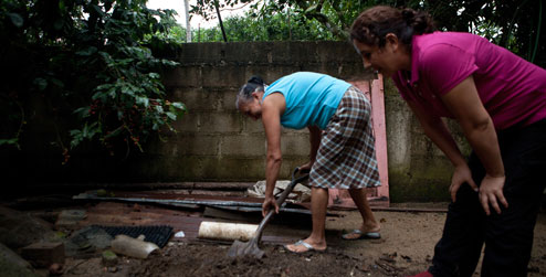 Milagros tending her garden watched by Karina